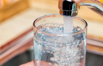 Glass under faucet filling with drinkable water