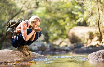 Woman drinking water from a river