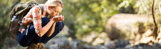 Woman drinking water from a river