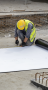 Two workers measuring roofing material